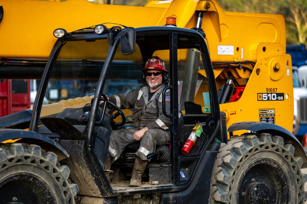 Candid portrait of oilfield equipment operator inside JCB telehandler, captured during live field operations.