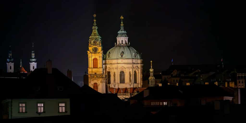 Nighttime view of St. Nicholas Church in Prague’s Malá Strana, illuminated against the dark skyline. Captured from across the rooftops using a telephoto lens while traveling light with the Bevis Gear bag.