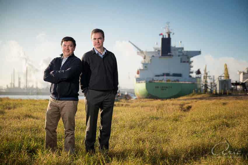 Two business leaders standing outdoors near an industrial port, with a cargo ship in the background.
