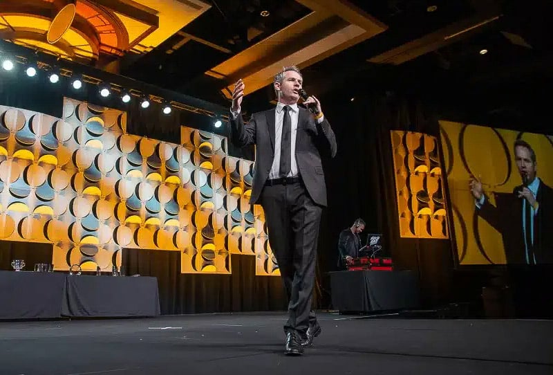 Conference keynote presentation with purple stage lighting, corporate event photography