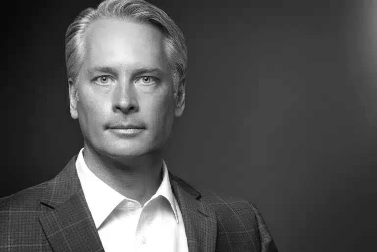 Male executive in suit and tie against grey studio backdrop, professional business headshot