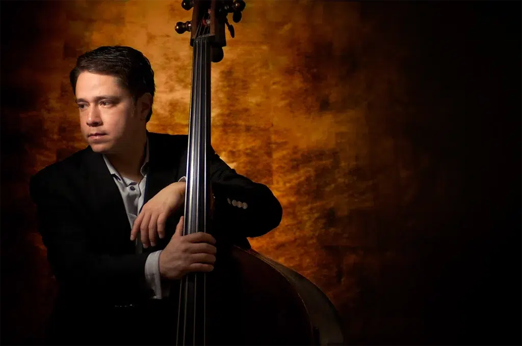 Bespoke executive portrait of professional musician with upright bass photographed with dramatic studio lighting and warm textured background for personal branding portrait
