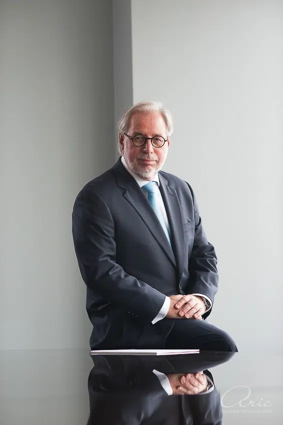 Professional executive headshot of senior business leader photographed with soft natural window lighting and shallow depth of field against clean neutral background for corporate profile