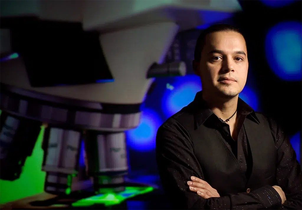 Environmental executive portrait of medical research professional beside laboratory microscope photographed with dramatic directional lighting and scientific background for leadership branding