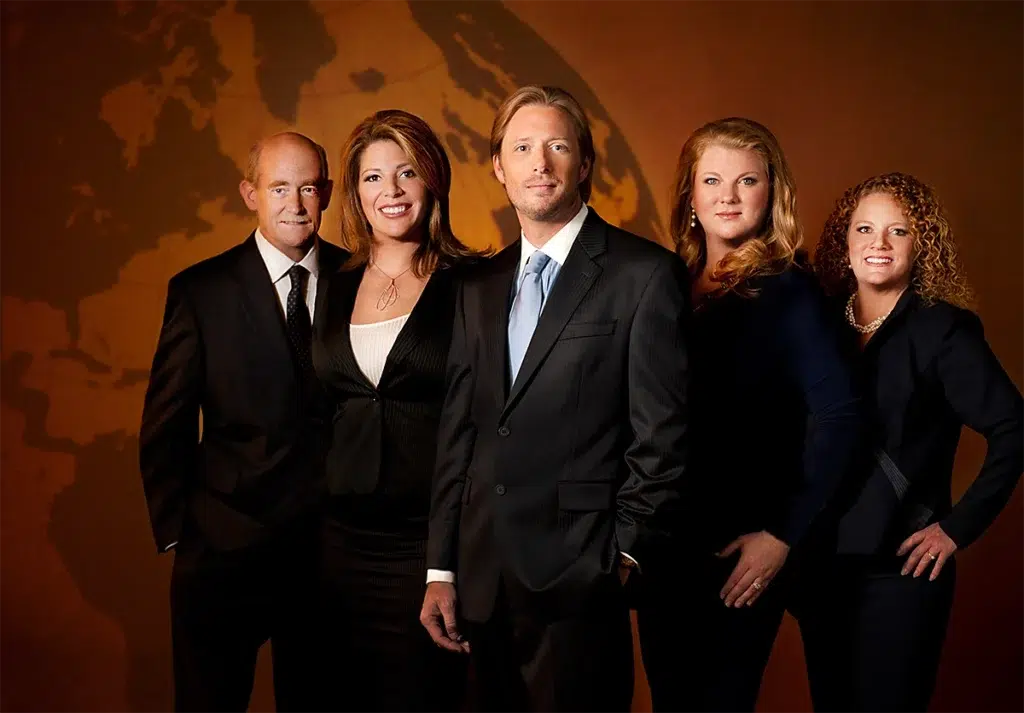 Corporate executive group portrait of business leadership team photographed with dramatic studio lighting and global map backdrop for professional company leadership profile
