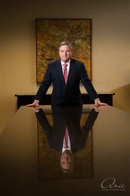 Professional executive portrait of corporate leader standing at boardroom table photographed with directional studio lighting and symmetrical composition for executive leadership branding