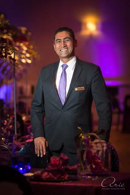 Environmental executive portrait of hospitality manager in upscale banquet venue photographed with soft off-camera lighting and shallow depth of field for leadership branding