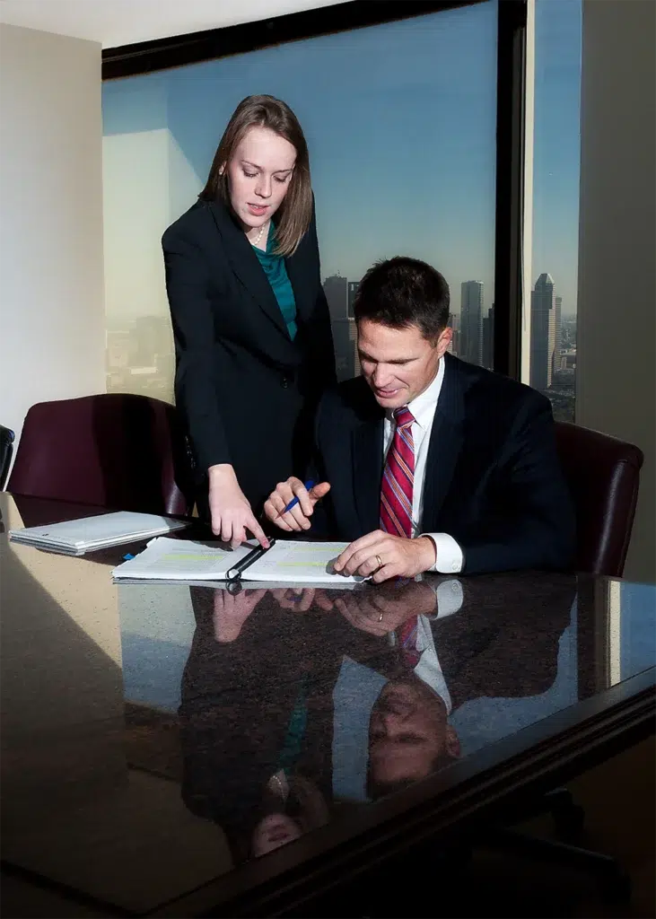 Environmental corporate leadership portrait of business professionals reviewing documents in modern office photographed with soft window lighting and shallow depth of field for executive branding
