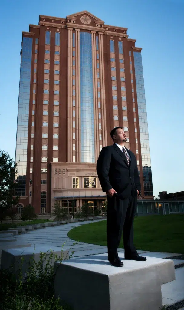 Environmental executive portrait of business professional photographed in front of tall corporate headquarters building with architectural composition and balanced off-camera lighting for leadership branding