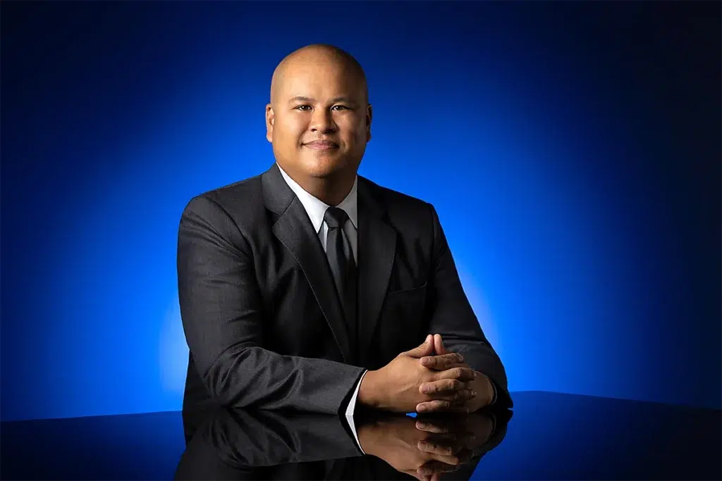 Studio executive portrait of corporate leader photographed with blue gradient background, controlled studio lighting, and reflective table composition for professional leadership branding