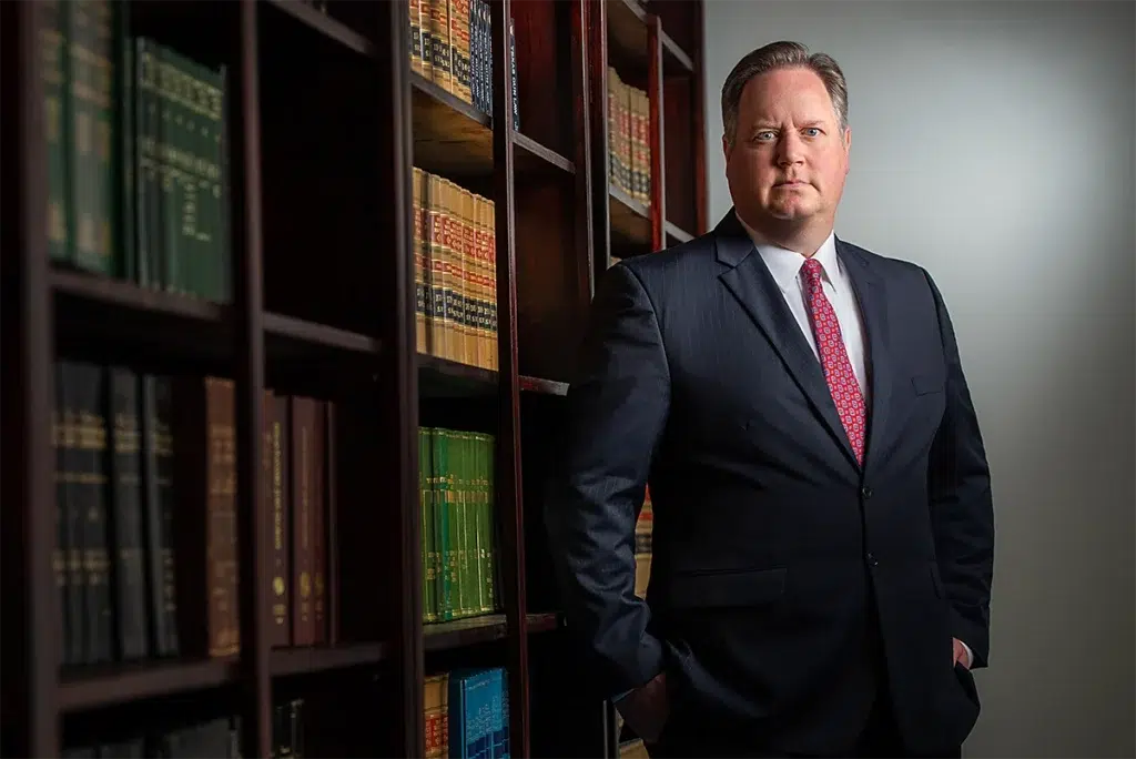 Bespoke executive portrait of senior attorney standing in law office library photographed with directional studio lighting and shallow depth of field for professional leadership branding