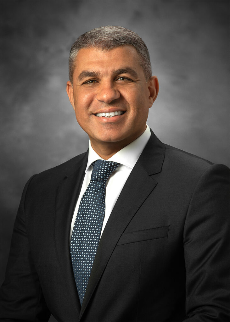 Executive corporate headshot after professional retouching with refined skin tone, softened facial lines, and improved background and lighting balance for a polished portrait