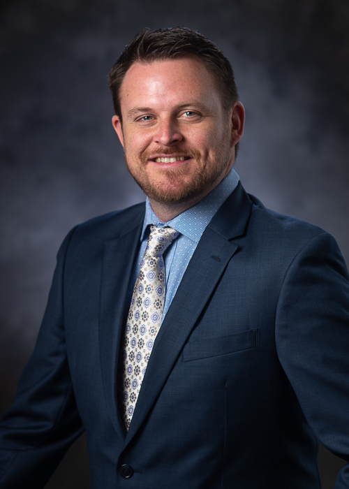 Corporate executive headshot before retouching showing natural skin texture, facial lines, and original studio lighting prior to portrait enhancement