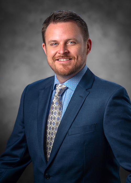 Executive corporate headshot after professional retouching with smoother skin tone, refined facial details, and enhanced background for a polished portrait