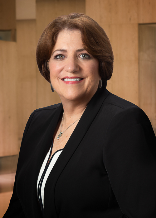 Professional corporate headshot after retouching with refined skin tone, softened facial lines, and enhanced background for a polished executive portrait