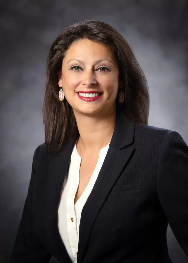 Professional corporate headshot of female executive photographed with soft studio lighting and neutral gray background for business profile and leadership branding