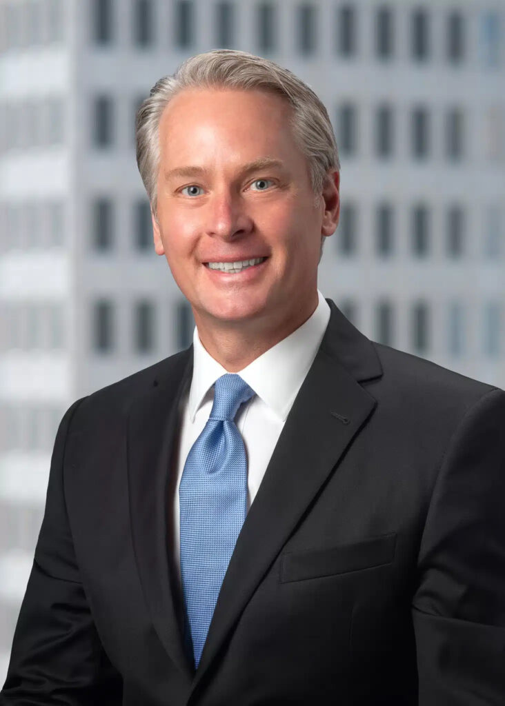 On-location corporate headshot of male executive photographed with soft natural light and modern office building background for professional business and LinkedIn branding
