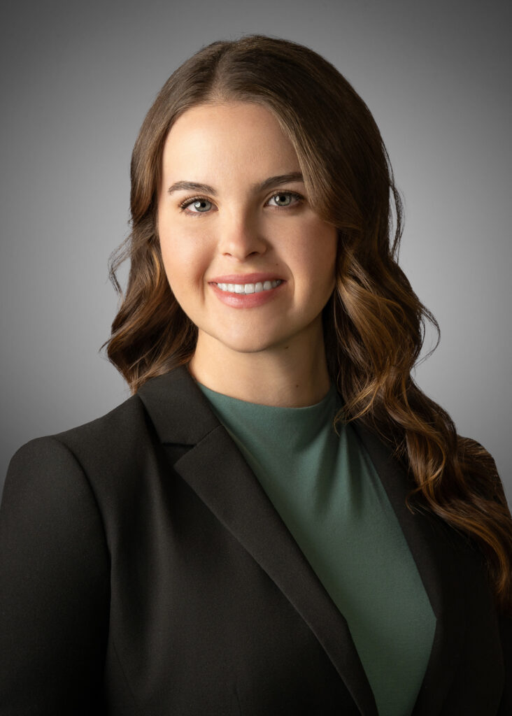 Professional studio headshot of female professional wearing black blazer and green top photographed with soft studio lighting and neutral gray background for corporate branding and LinkedIn profile. For Headshot Photography Portfolio