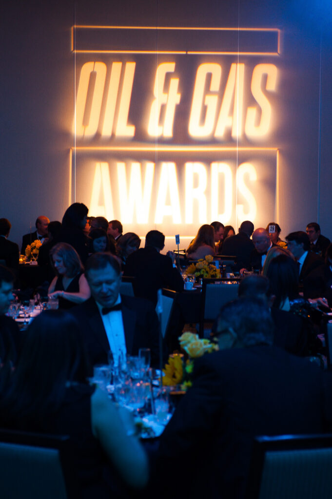 Guests seated at round tables during the Oil & Gas Awards, with large projected event branding on the wall behind them.