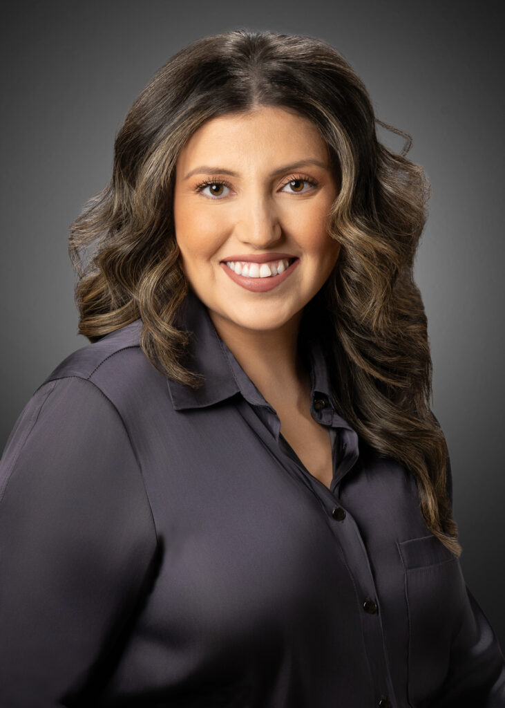 In-studio headshot of a professional woman against a gray vignette background.