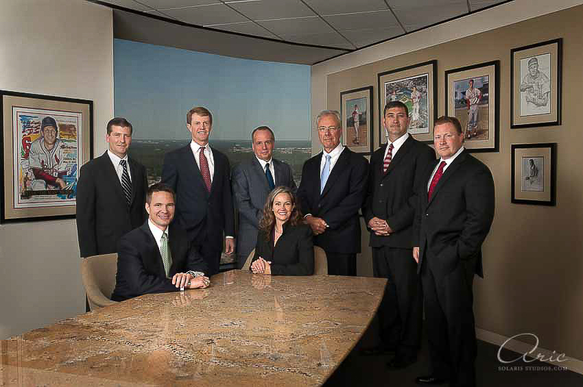 Executive group portrait of a leadership team in a downtown Houston office conference room with city views visible through a large window.