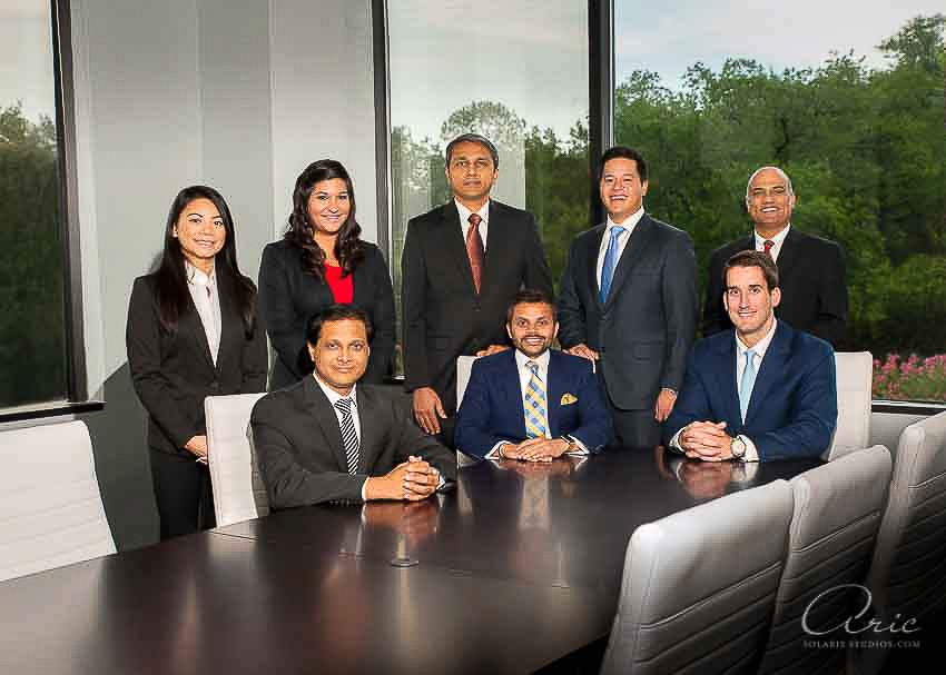 Executive group portrait of a leadership team in a conference room with large plate glass windows, photographed with carefully balanced interior and exterior light.