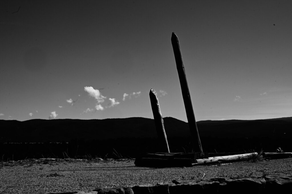 A black and white landscape image, with a old ladder leading underground.